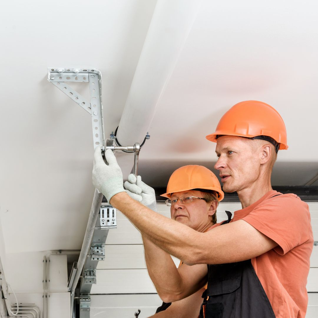 Two garage door repair men working on garage door