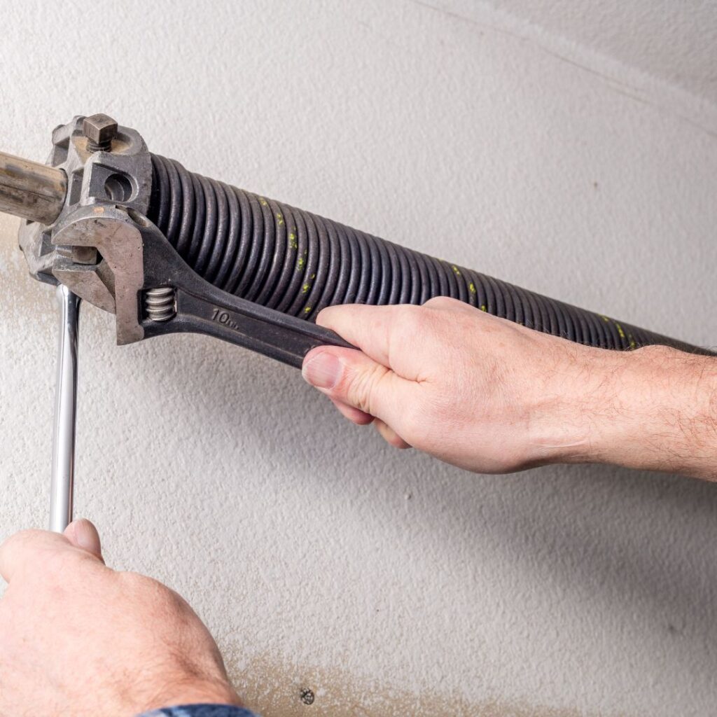 repairman fixing a garage door spring