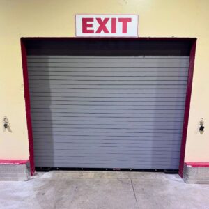 Grey rolling security door beneath a red EXIT sign.