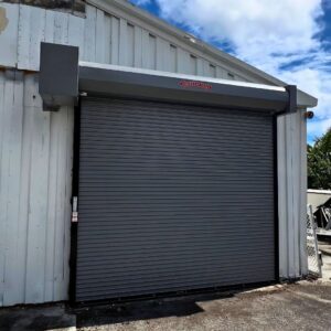 Grey industrial roll-up door on corrugated metal warehouse.